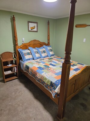 A four-poster bed with a quilt, a wicker side table, and a framed picture on the wall. - Cabin with spacious yard north of Dover Ar.  National Forest, Moccasin Gap ATV (Dover)