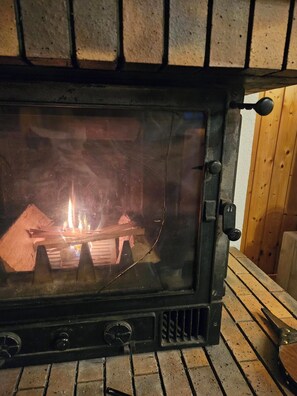 Ein Holzofen mit Glastür, Bedienfeld und einem Metallrost.