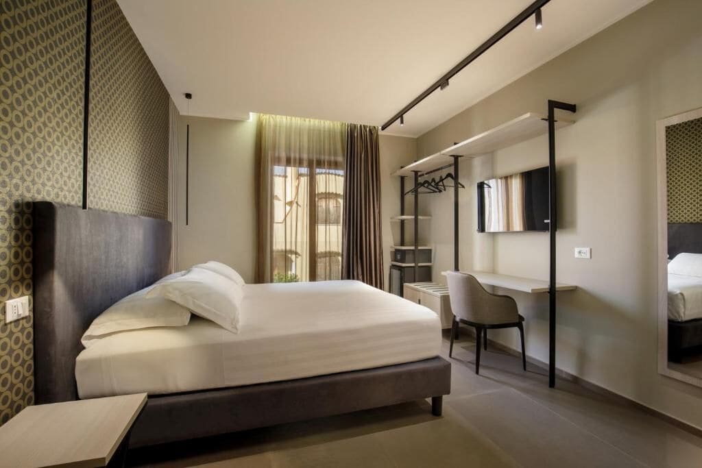 Een moderne hotelkamer met een bed, bureau, stoel en een televisie.