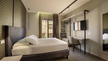 Een moderne hotelkamer met een bed, bureau, stoel en een televisie.