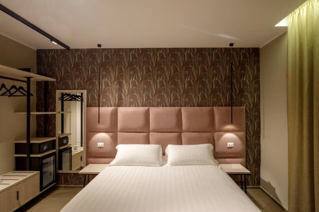 A modern bedroom with a large bed, bedside tables, a wardrobe, and a mirror.