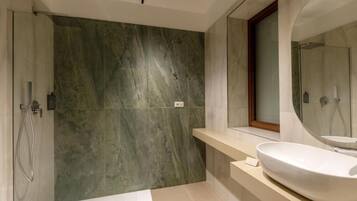 A modern bathroom with a large mirror, a freestanding bathtub, and a marble wall.