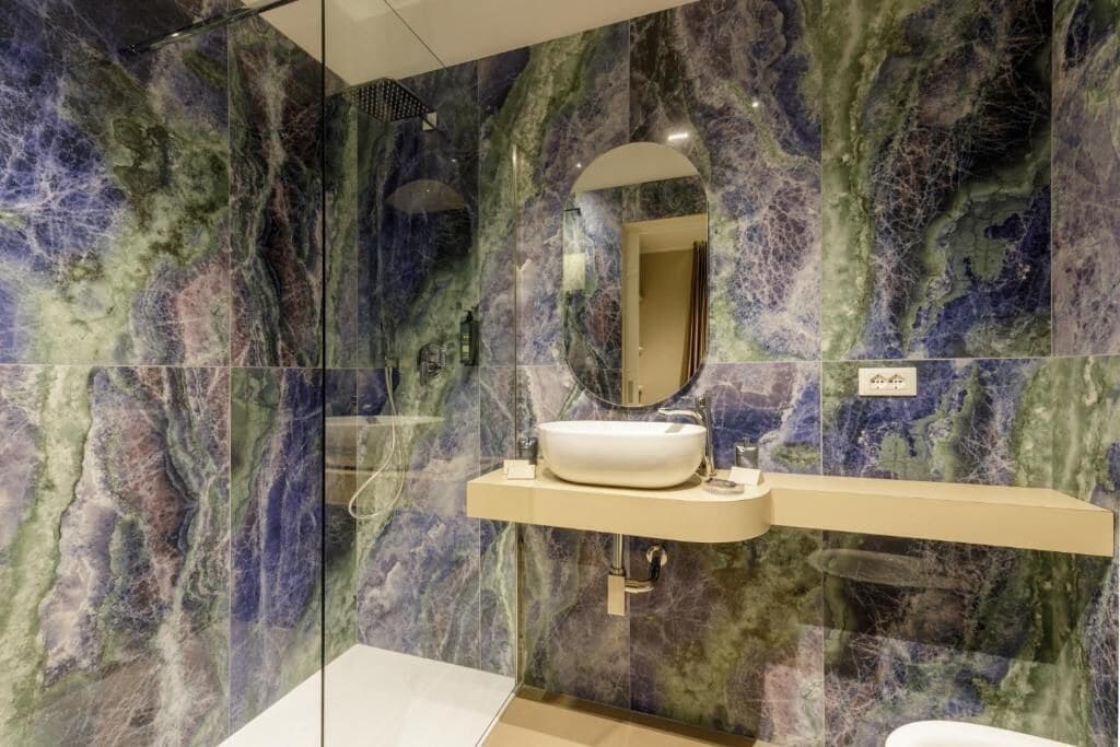 Ein Badezimmer mit Marmorwand, einem Waschbecken und einem Spiegel.