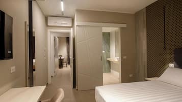 A hotel room with a bed, a desk, and a chair. There is a door leading to a bathroom and a hallway.