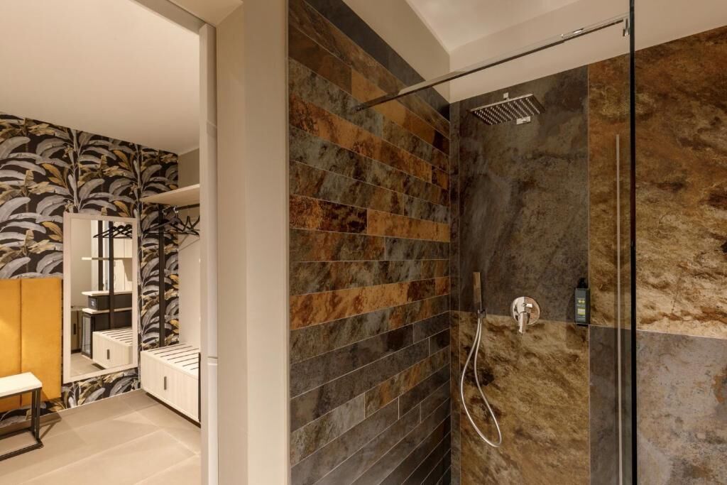 A modern bathroom with a shower, tiled walls, and a mirror.