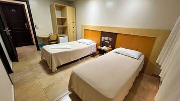 A hotel room with two beds, a desk, a wardrobe, and a bathroom.