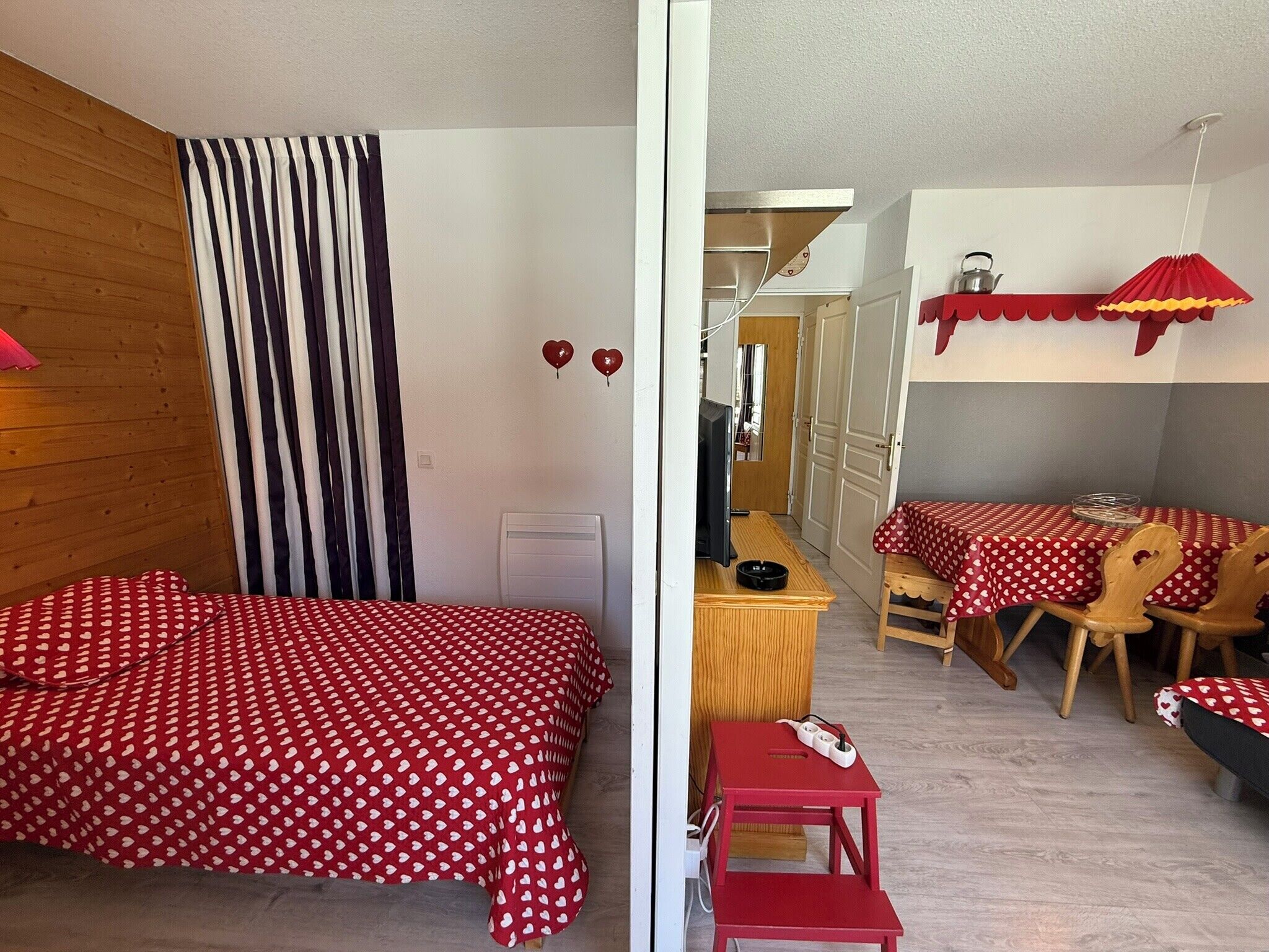 Ein Zimmer mit einem Bett, einem Schreibtisch, einem Stuhl und einem Tisch mit rotem Tischlein.
