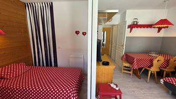 Ein Zimmer mit einem Bett, einem Schreibtisch, einem Stuhl und einem Tisch mit rotem Tischlein.