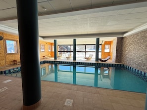 Piscina interior con vistas a un paisaje nevado a través de amplios ventanales.