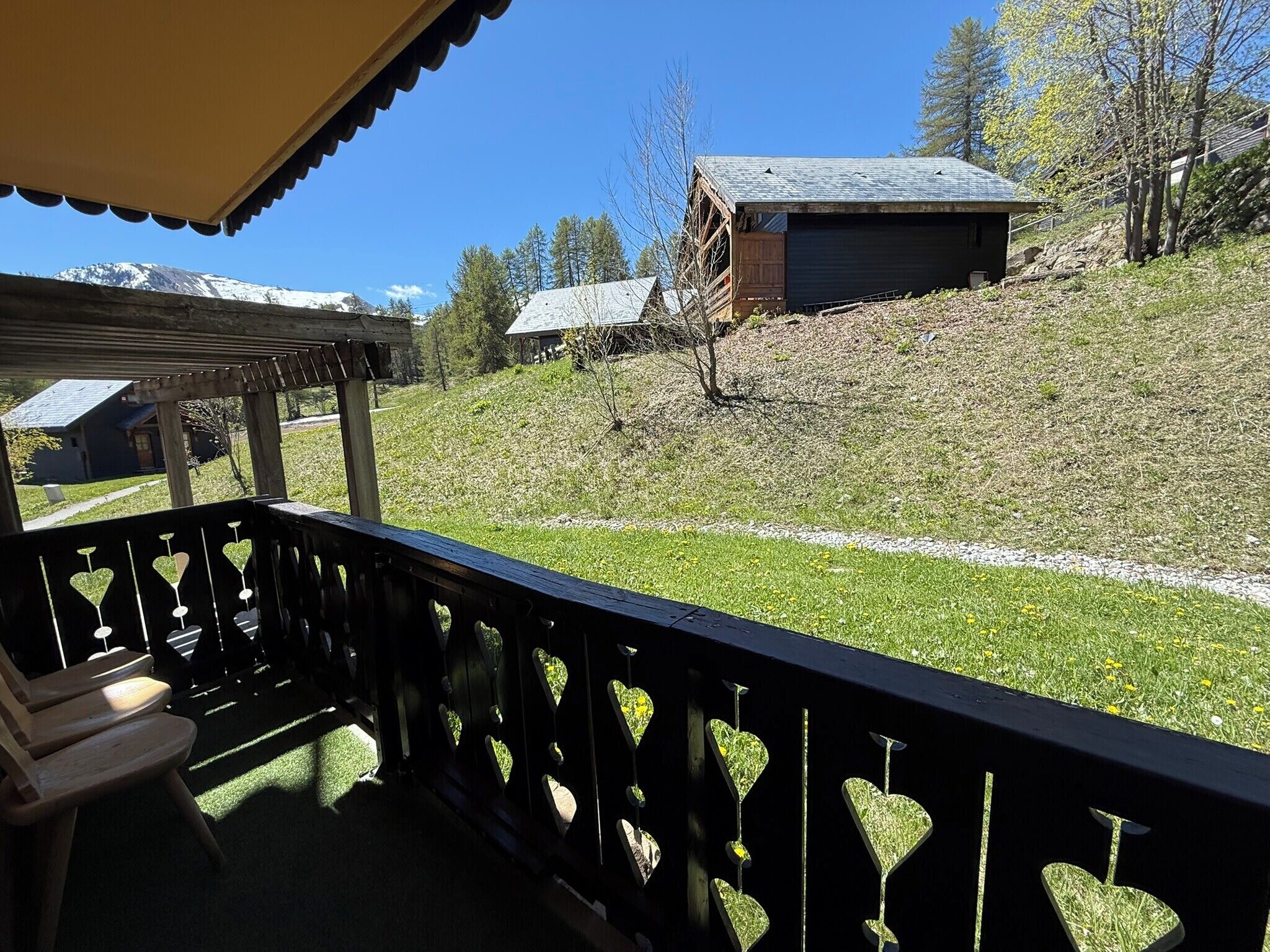 Un pontile in legno con decorazioni a forma di cuore, vista su una montagna e un piccolo edificio su una collina.