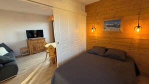 Quarto com cama, televisão, escrivaninha e cadeira.