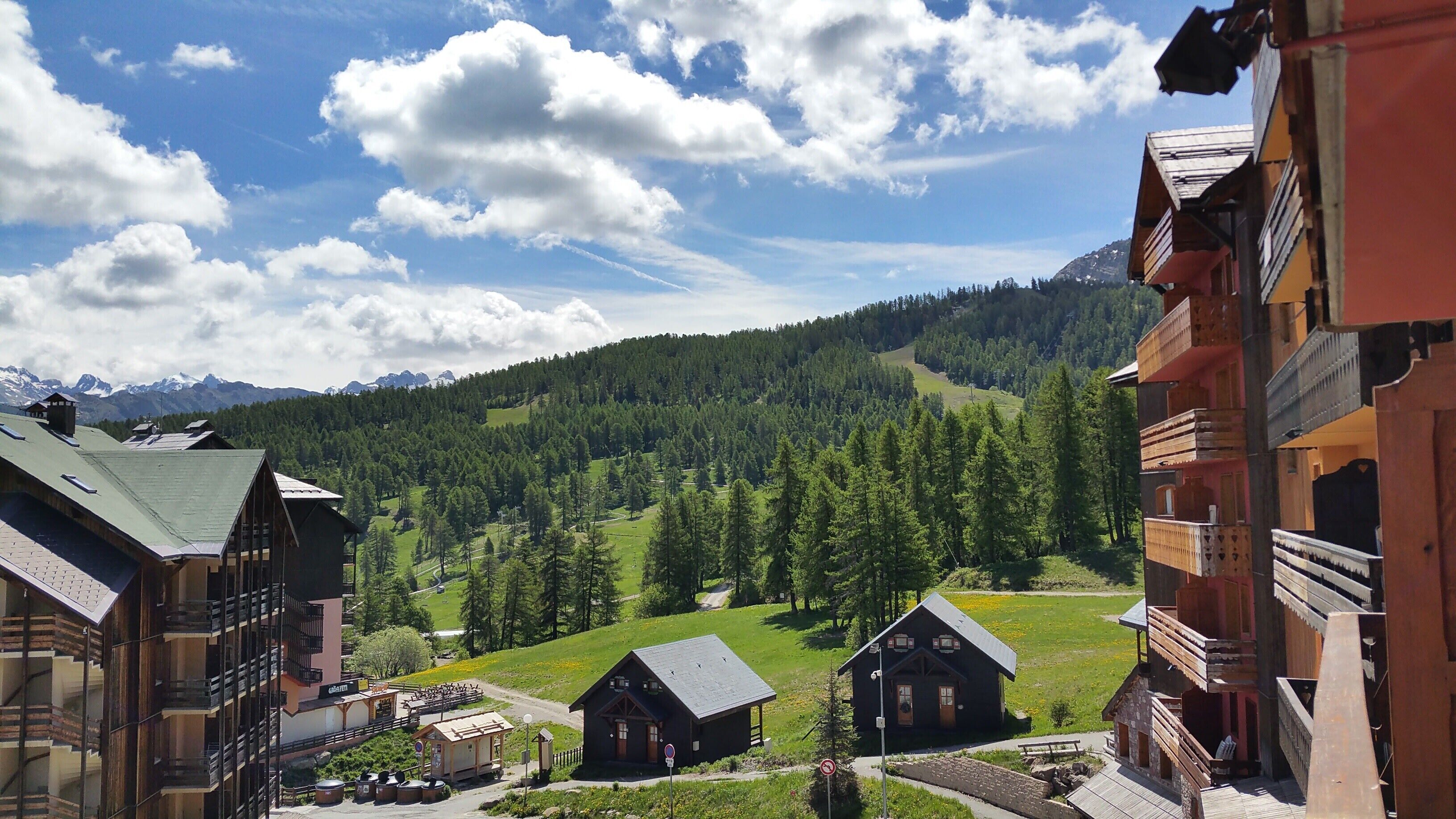Ein Bergdorf mit traditionellen Holzhäusern, einem klaren Himmel und Blick auf den umliegenden Wald und die Berge.