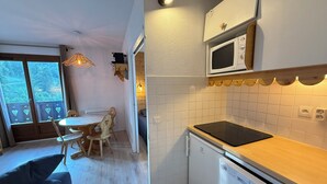 Uma cozinha compacta com micro-ondas, lava-louças e um pequeno espaço de refeições com mesa e cadeiras.