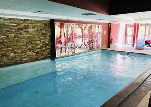 An indoor swimming pool with a stone wall and a mural. - Risoul • T2 6 pers • Piscine et sauna • Skis aux pieds (Risoul 1850)
