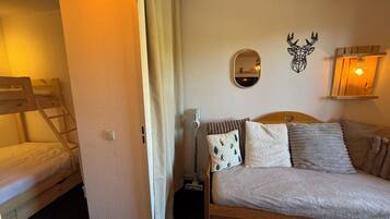 A bedroom with a bunk bed, a single bed, a mirror, a wall-mounted light, and a decorative deer head.