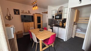 Une cuisine compacte comprenant un coin repas, un four à micro-ondes et un petit réfrigérateur.