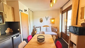 Un espace de vie compact comprenant une table à manger, des chaises rouges, un canapé, un coin cuisine avec une cuisinière et un four à micro-ondes.
