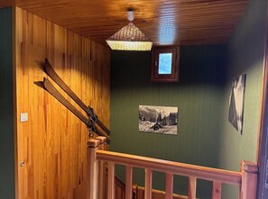 A wooden staircase with a hanging light fixture and a framed picture on the wall.