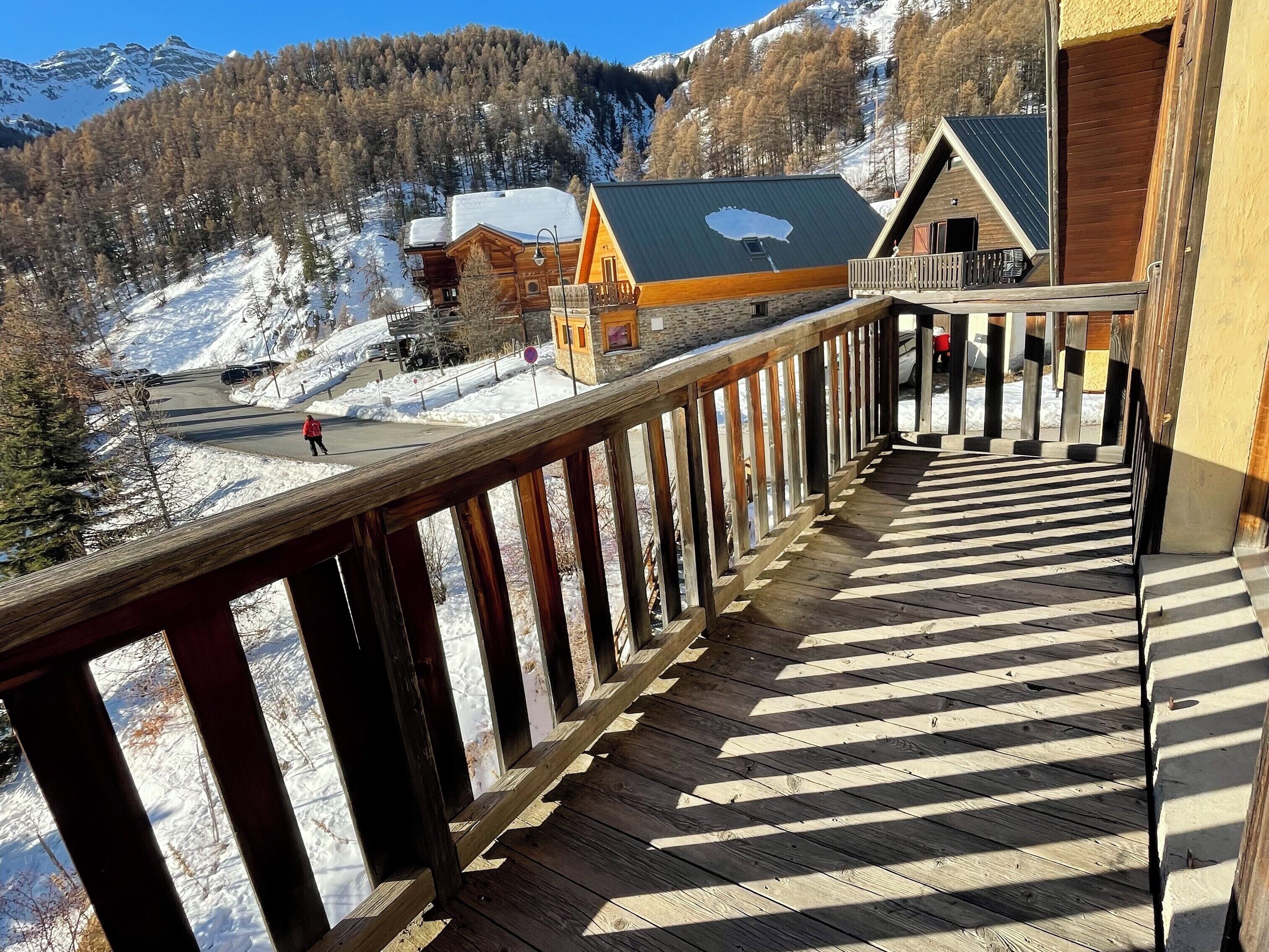 A wooden deck with a view of a mountain resort.
