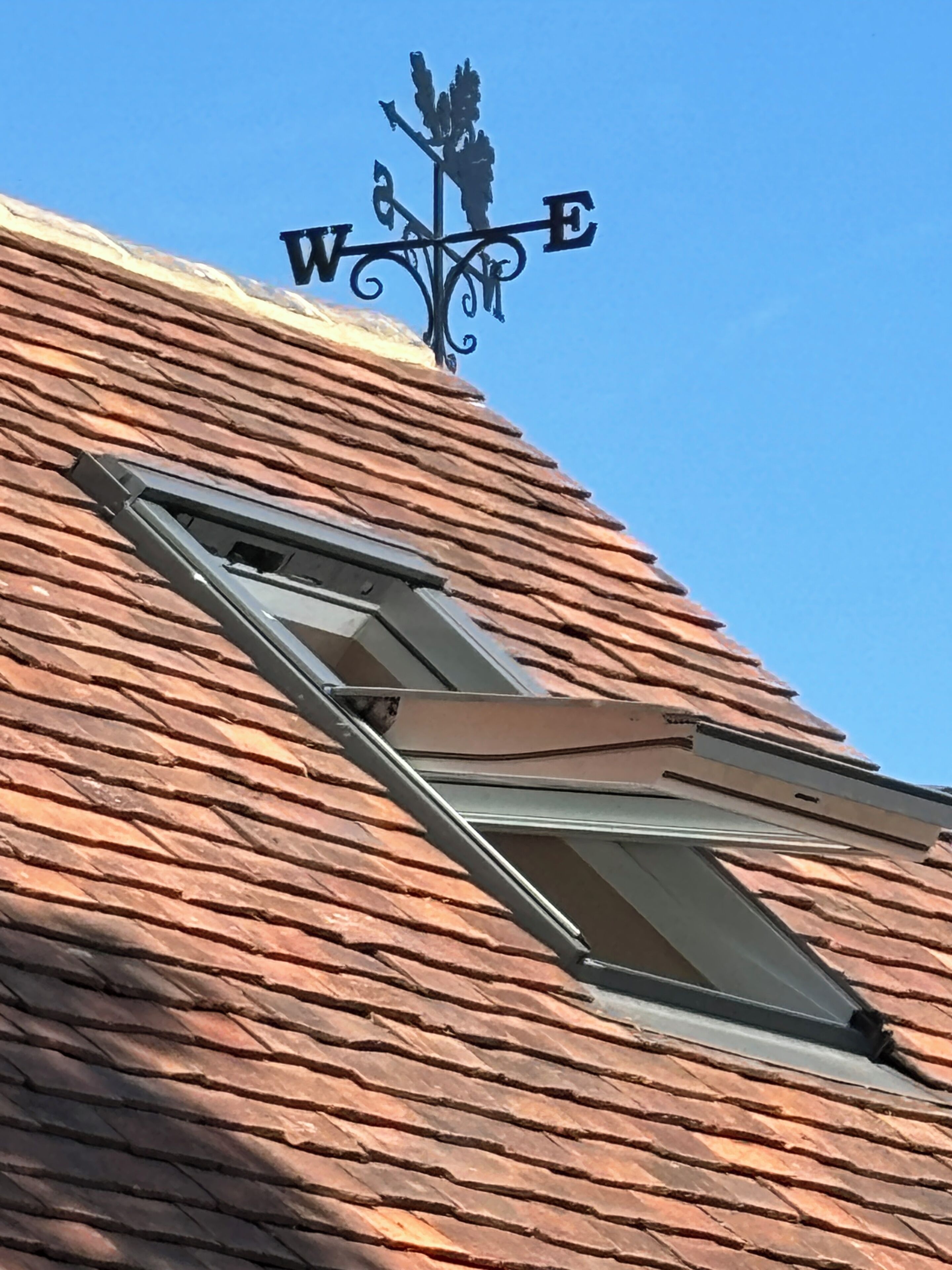 Un bâtiment doté d’un toit en pente, d’une fenêtre et d’une girouette indiquant la direction du vent.