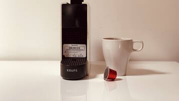 A black and white coffee maker with a label and a red cup beside it.