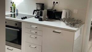 Una cocina moderna con armarios blancos, una cafetera negra, un tostador y una tetera.