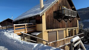Uma cabana de madeira com varanda, rodeada por neve.