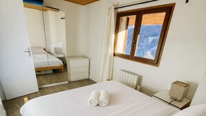 Une chambre à coucher comprenant un lit, une table de chevet, une commode, une fenêtre avec vue et un radiateur.
