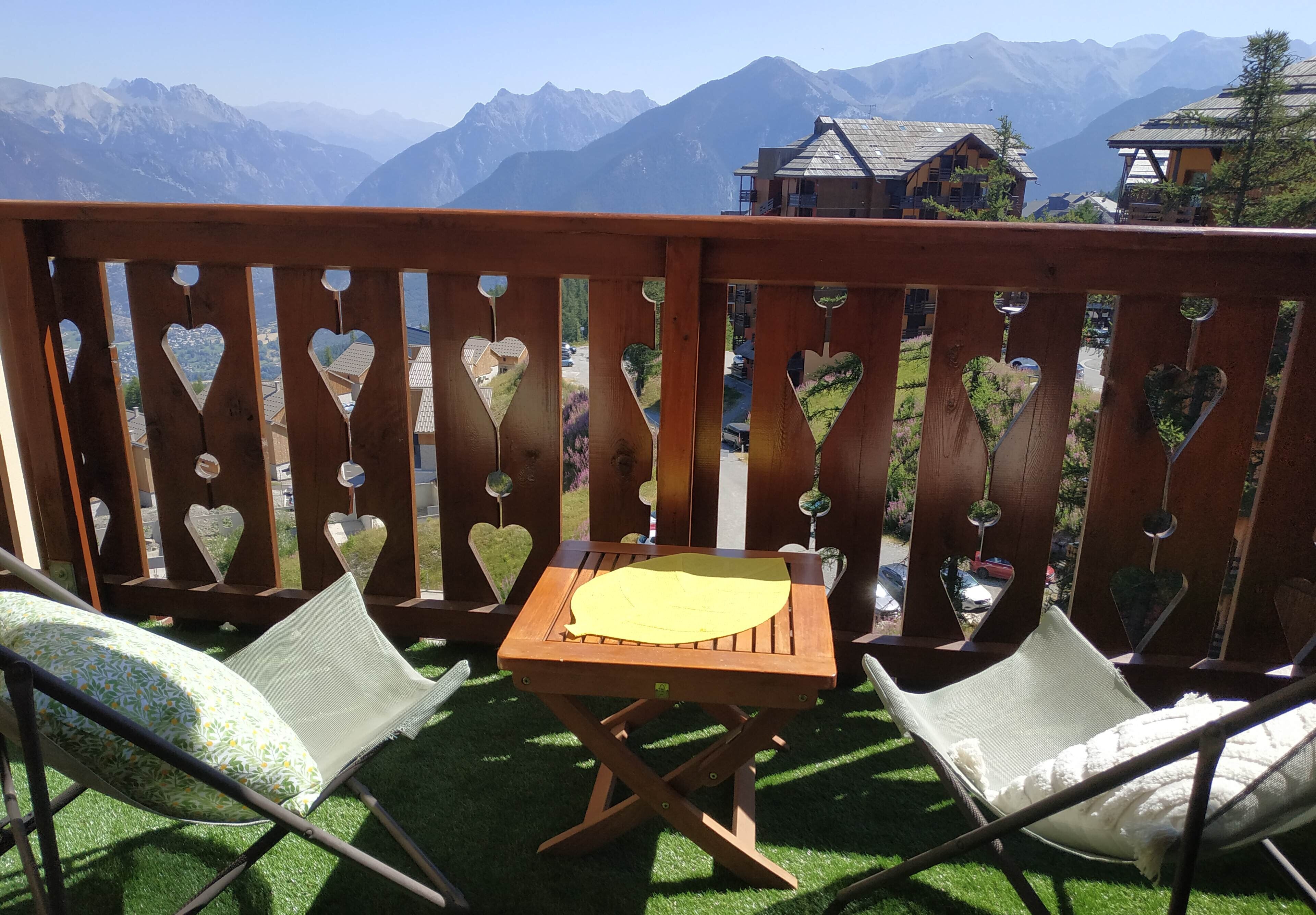 A wooden deck with heart-shaped cutouts, a small table, and two chairs.