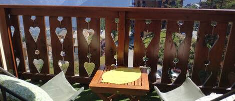 A wooden deck with heart-shaped cutouts, a small table, and two chairs.