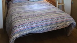 A bunk bed with a ladder, a bedside lamp, and a patterned bedspread.