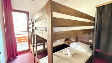 A bunk bed room with a window, a door, and a red curtain.