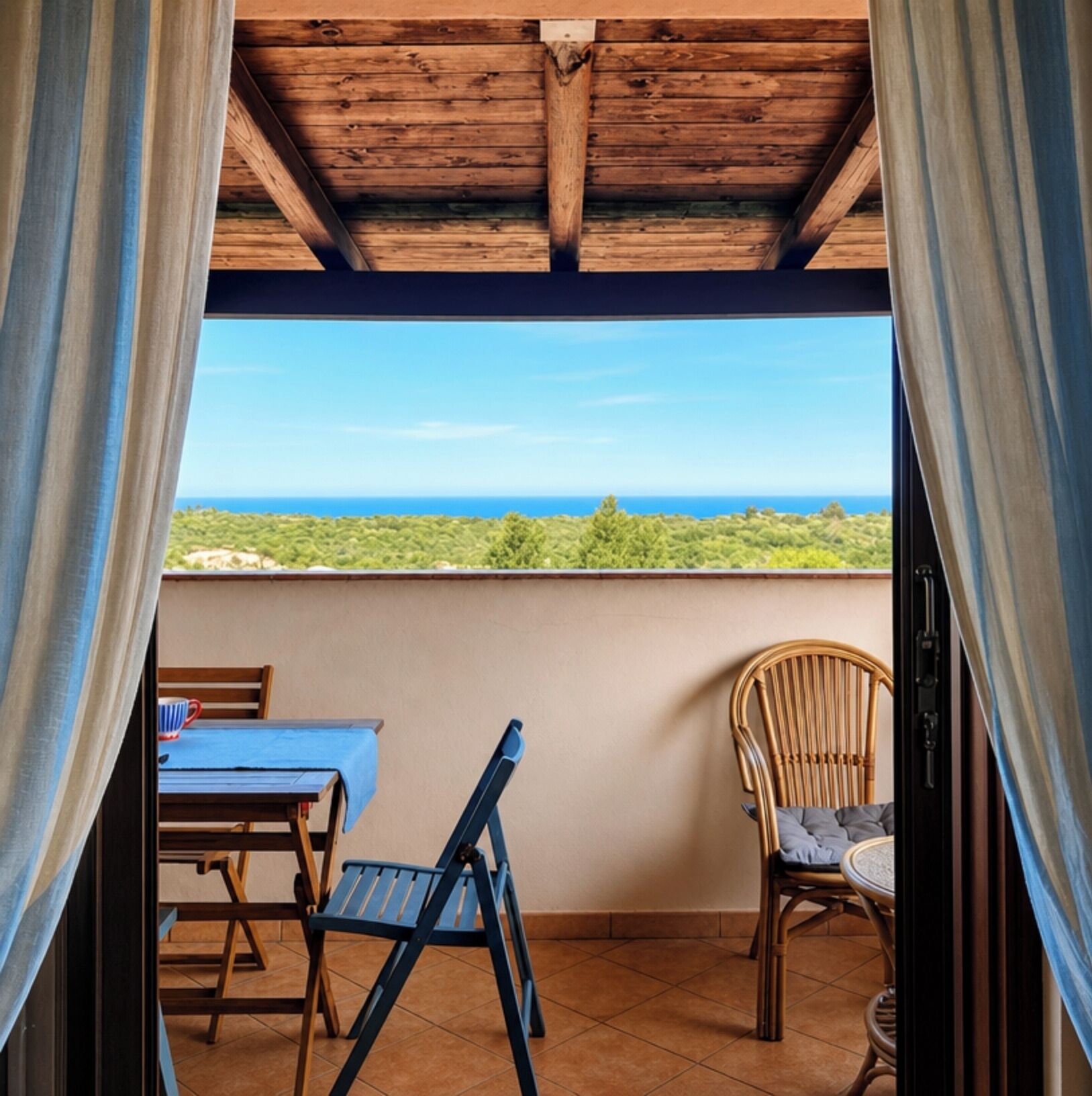 A balcony with a view of the sea, a table, and two chairs.