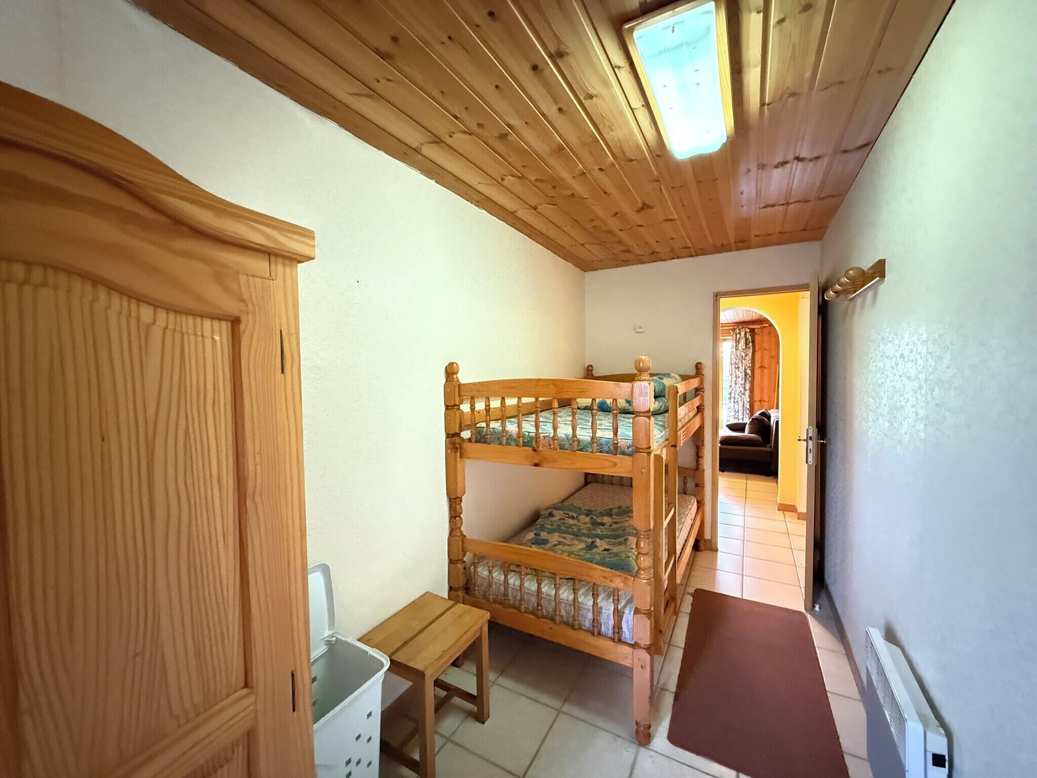 Una habitación con literas, un armario de madera, una mesita y un radiador.