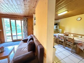 En inredning med träpanel, en soffa, ett matbord och stolar.