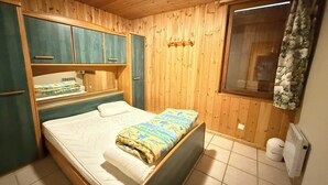 Ein Schlafzimmer mit Bett, Kleiderschrank, Fenster und Heizkörper.