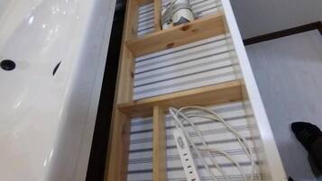 A bathroom with a white sink, a wooden shelf with striped towels, and a white power strip.