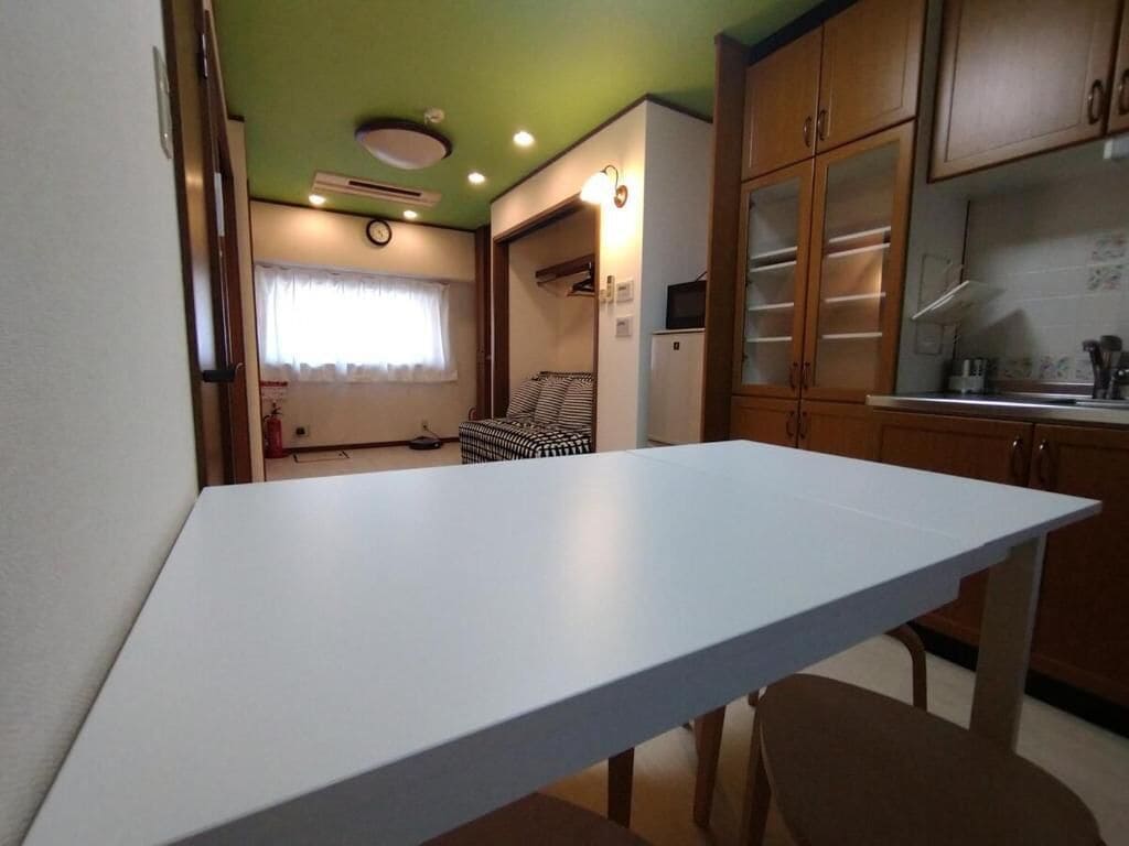 A compact kitchen with a white countertop, wooden cabinets, and a small refrigerator.