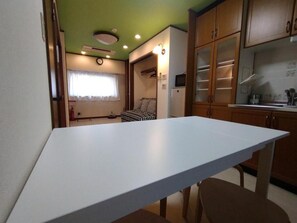 Eine kleine Küche mit weißer Arbeitsplatte, Holzschränken und einem kleinen Kühlschrank.