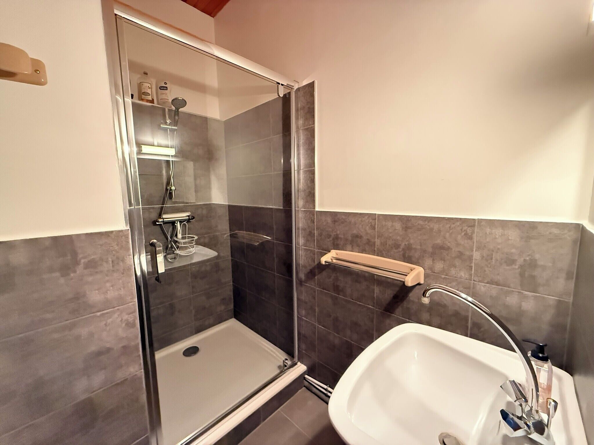 A bathroom with a glass-enclosed shower, a white sink, and a towel rack.