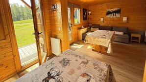 Ein Holzblockbau-Innenraum mit zwei Betten, einer Couch und einem Esstisch.