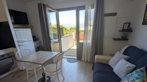 Un espacio habitable compacto con kitchenette, comedor, sofá y un balcón con vistas.