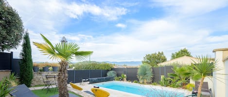 Um quintal com piscina, gramado verde e mobiliário de exterior.