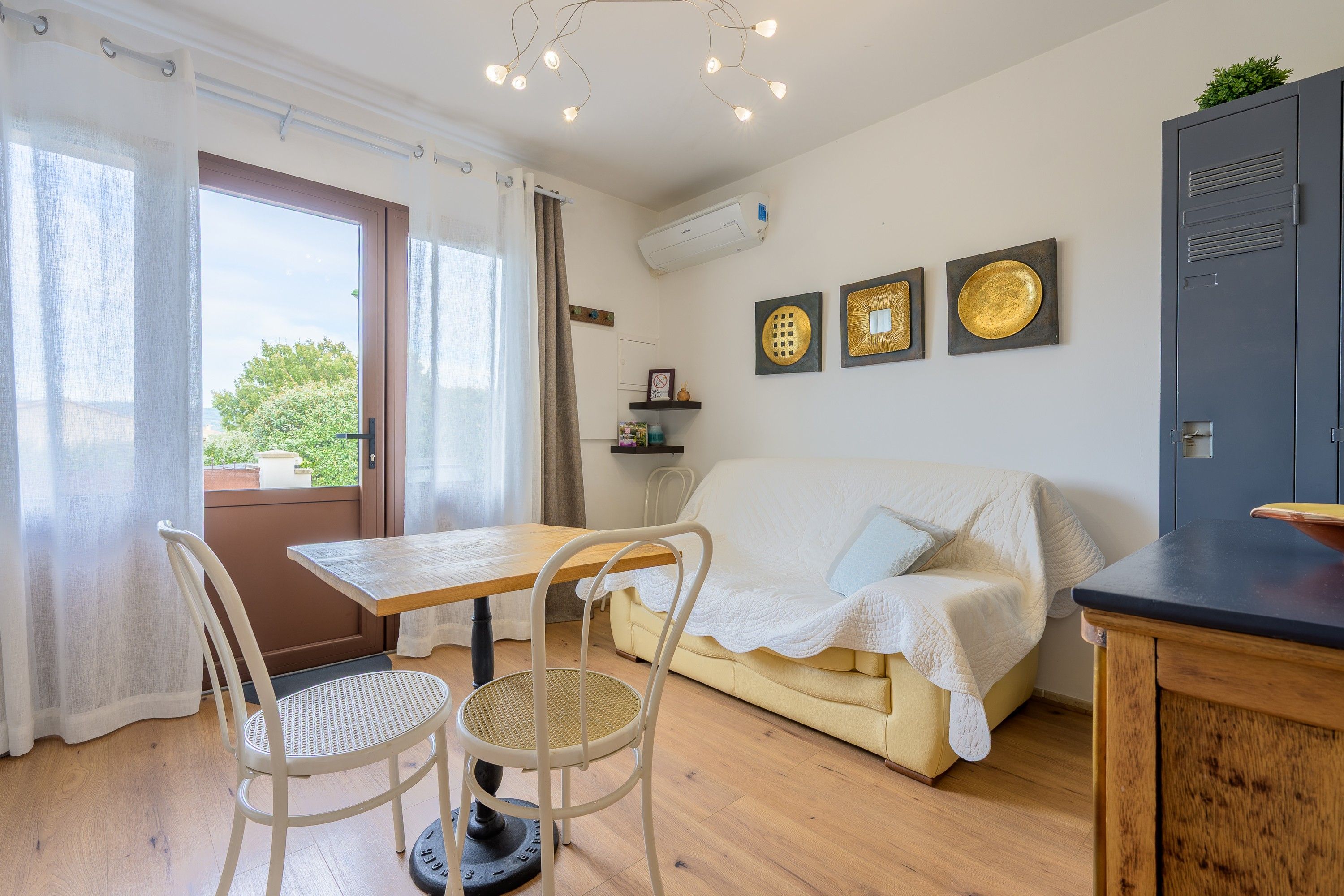 A room with a wooden table, two chairs, a sofa, and a cabinet.