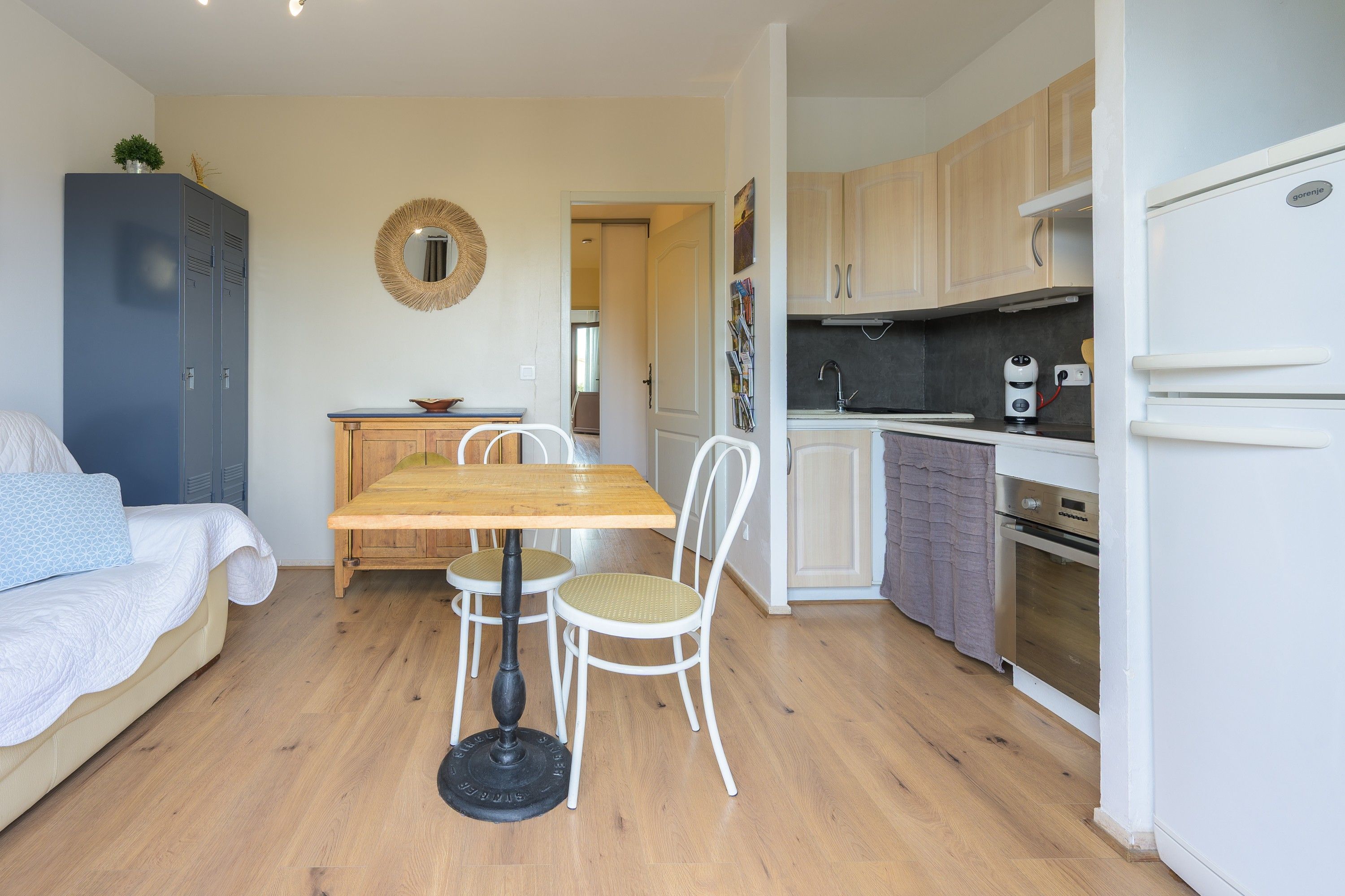 A compact living space with a dining area, kitchenette, and a bed.
