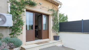 A residential building with a brown door, a large air conditioning unit, and a potted plant.