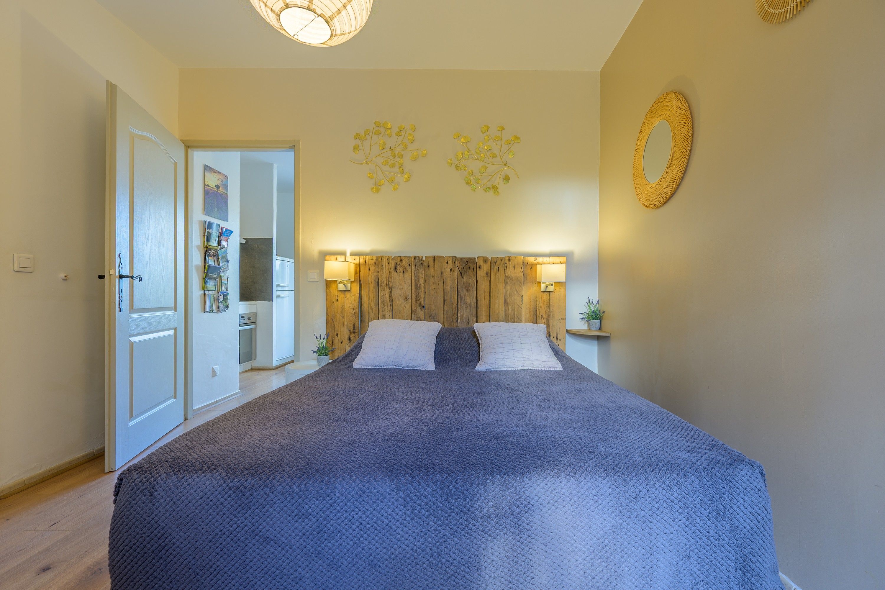 Ein Schlafzimmer mit einem großen Bett, einem Holzkopfteil, Nachttischlampen und einem Wandspiegel.