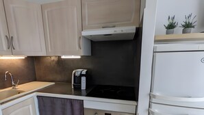 Cocina compacta con lavamanos, cafetera, horno y refrigerador.