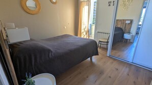 Un dormitorio con cama, una mesita de noche con lámpara, un espejo y vistas a un balcón.