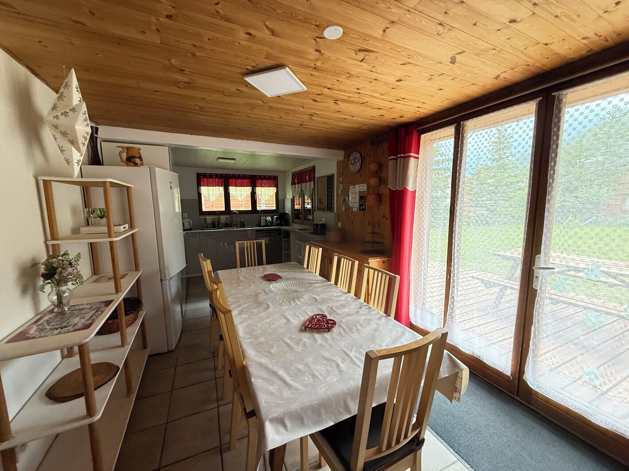 Una cocina acogedora con armarios de madera, una mesa de comedor preparada para cuatro personas y un ventanal con vistas al exterior.